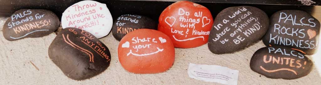 painted rocks with motivational sayings: palcs stands for kindness, throw kindness around like confetti, you can do anything, share your smile, do all things with love and kindness, in a world where you can be anything, be kind, palcs kindness rocks, palcs unites